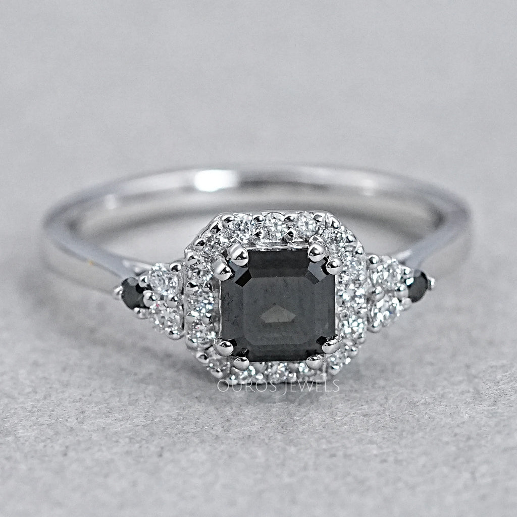 top view of asscher cut black diamond halo engagement ring on grey background