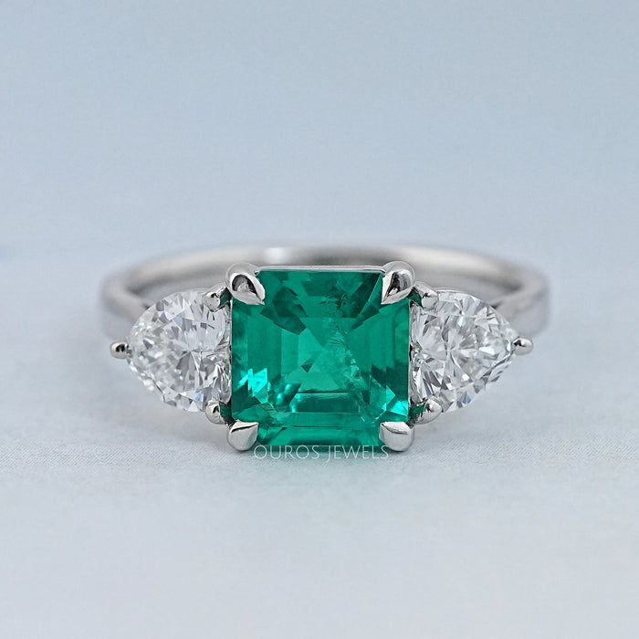 front view of green asscher gemstone with heart lab diamond three stone engagement ring