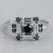 top view of black round diamond baguette halo engagement ring on grey fabric