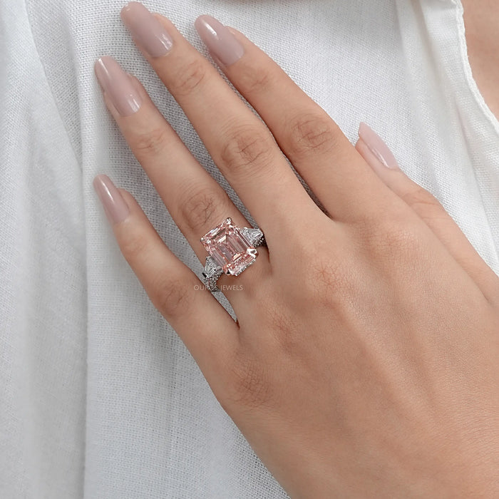 pink emerald lab diamond three-stone hidden halo colored engagement ring in finger