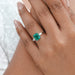 green emerald gemstone pear diamond three stone engagement ring on model's finger