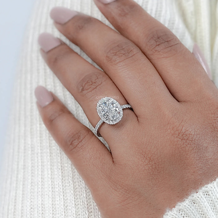 oval cut lab diamond halo engagement ring on model's finger