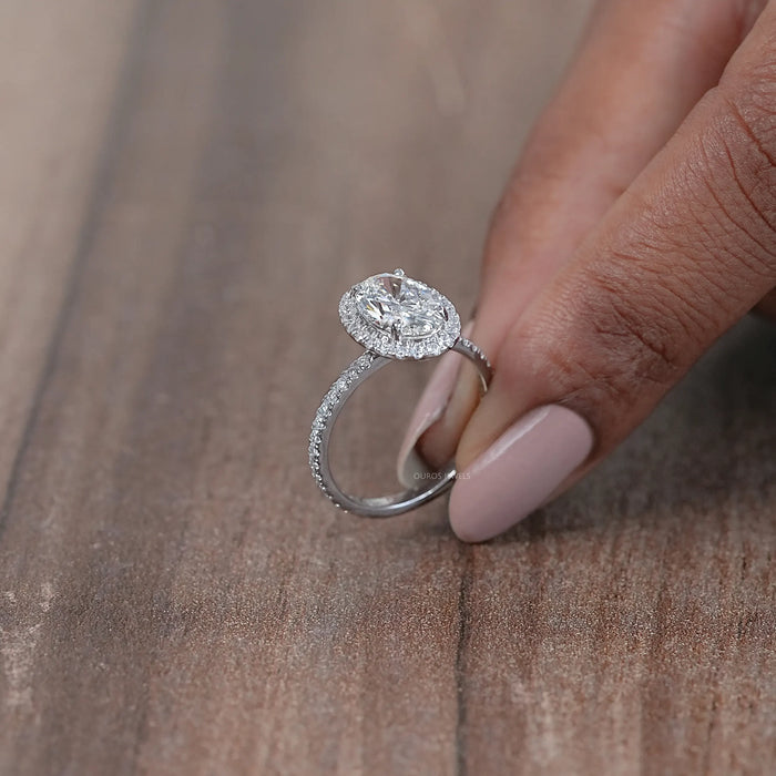 side view of oval cut lab diamond halo engagement ring on brown background