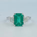 front view of green emerald gemstone with trapezoid diamond 3 stone engagement ring
