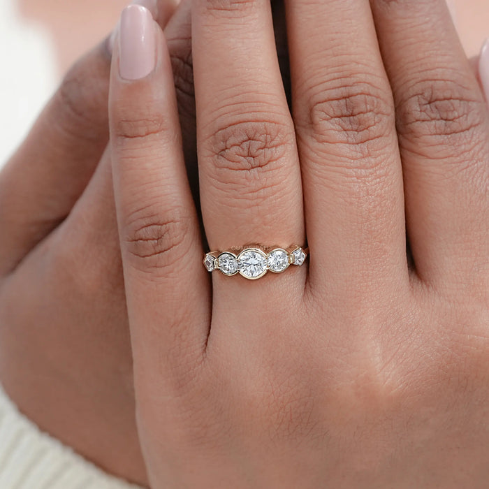 round and pentagon lab diamond bezel set five stone wedding ring on model's finger