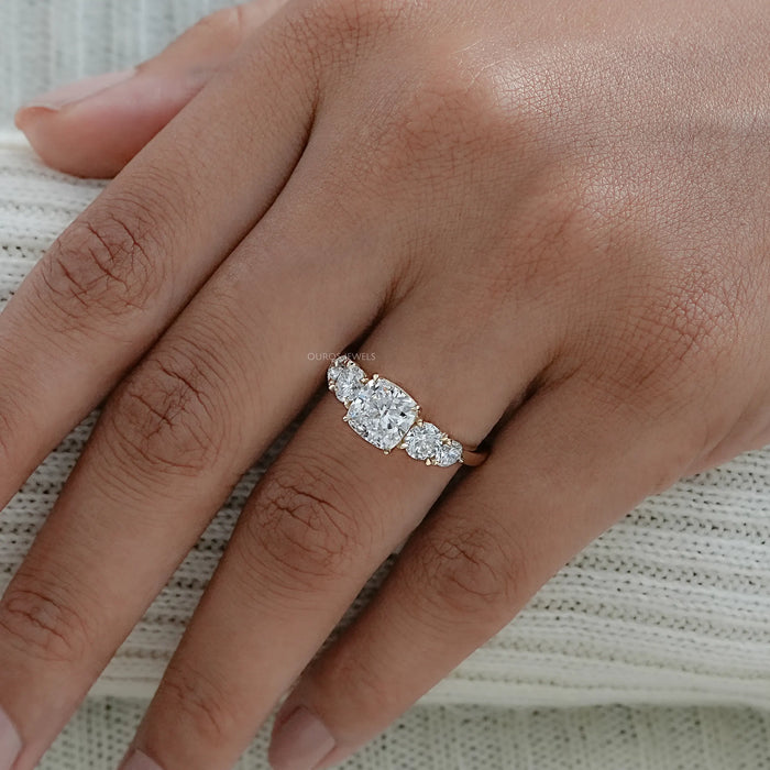 cushion cut diamond five stone engagement ring in yellow gold band in finger