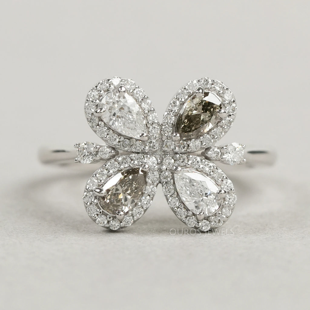 top view of olive pear cut lab diamond floral halo engagement ring on grey fabric