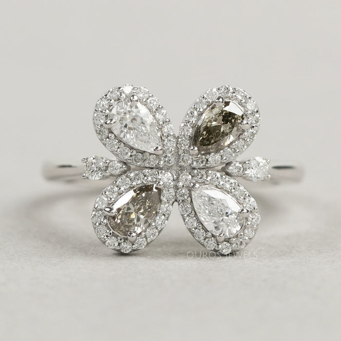 top view of olive pear cut lab diamond floral halo engagement ring on grey fabric