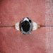 front view of black oval cut diamond three stone engagement ring in jewelry box