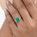 green emerald gemstone with shield diamond 3 stone engagement ring on model's finger