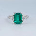front view of emerald gemstone and triangle cut lab diamond three stone engagement ring