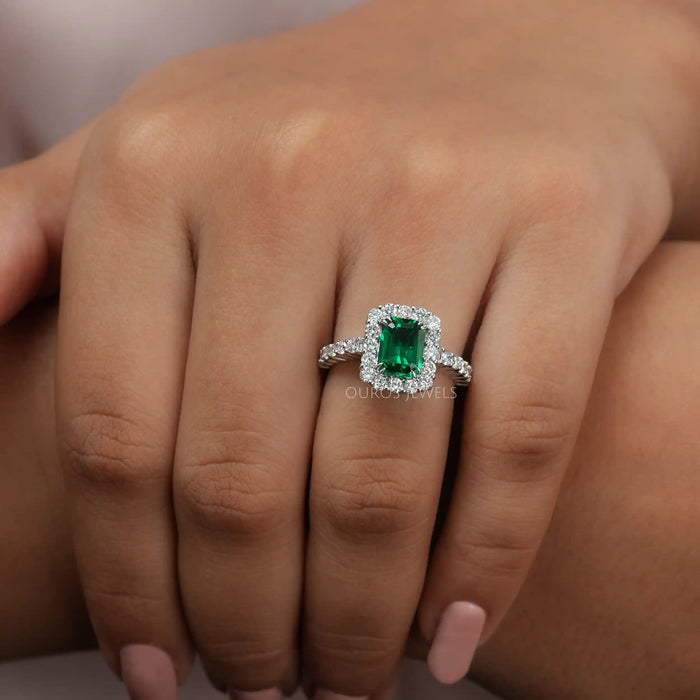 green emerald cut gemstone halo engagement ring white gold in finger
