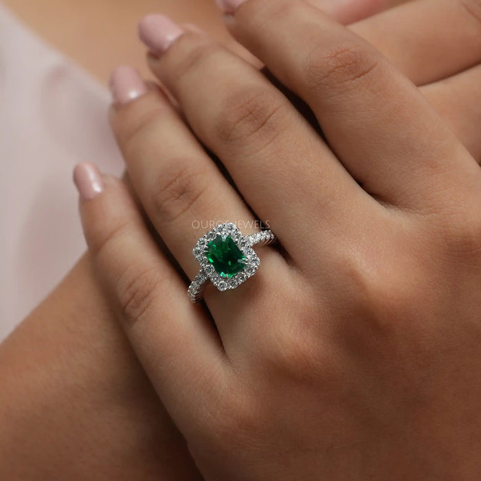 green emerald cut halo diamond wedding ring white gold on model's finger