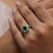 green emerald cut halo diamond wedding ring white gold on model's finger