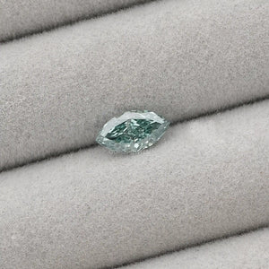 1.23 Carat Green Marquise Cut Loose Diamond placed on a light gray fabric background