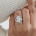 elongated cushion diamond with baguette and round halo wedding ring in model's finger