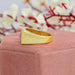 side view of pink round cut diamond halo yellow gold men's wedding band on jewelry box