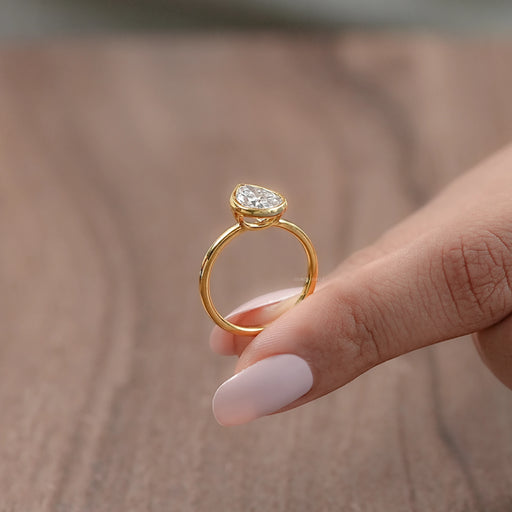 side view of bezel set engagement ring featuring a pear-cut diamond