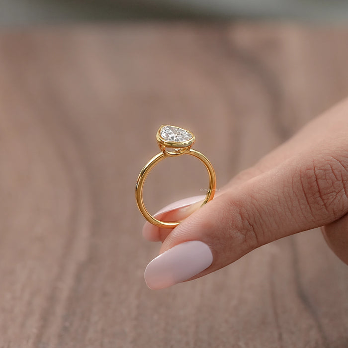 side view of bezel set engagement ring featuring a pear-cut diamond