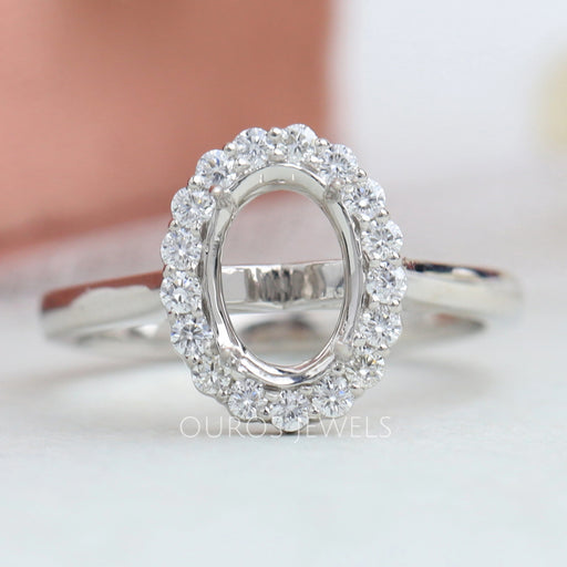 front view of oval-shaped halo semi-mount engagement ring on grey fabric