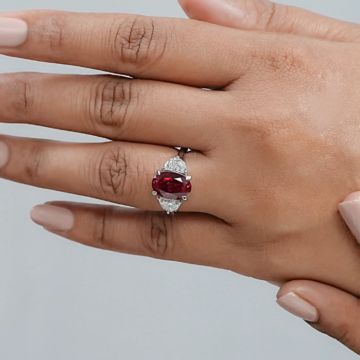 oval ruby gemstone and half moon diamond 3 stone engagement ring in finger