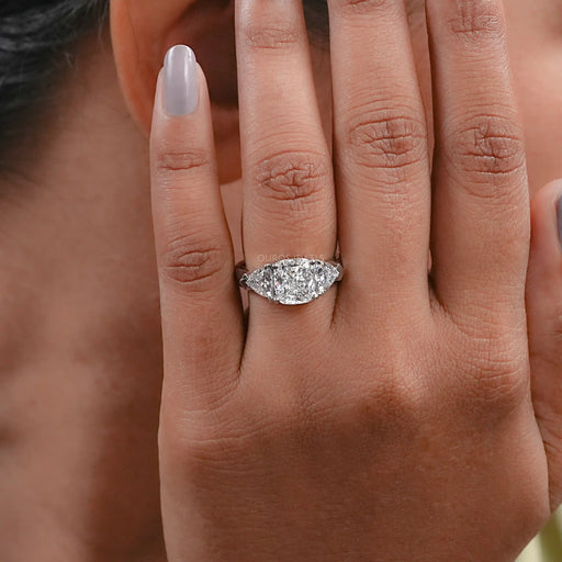 cushion cut lab diamond three stone engagement ring in finger