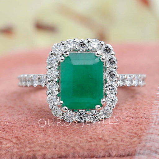 green emerald cut gemstone halo engagement ring's front view on box