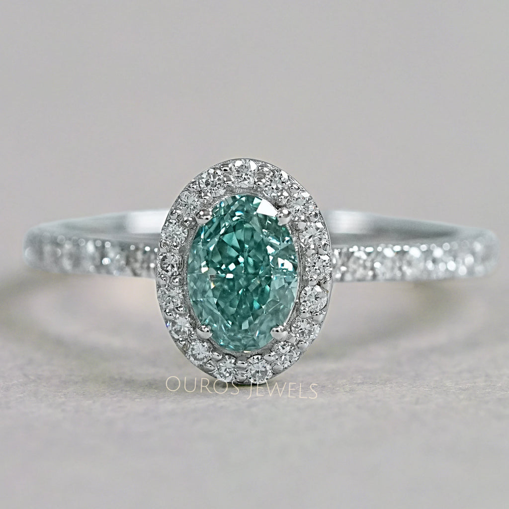 top view of fancy vivid green oval cut diamond halo wedding ring on grey fabric