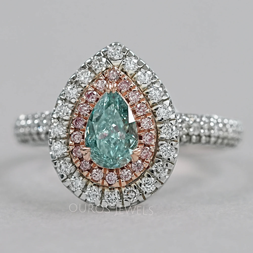 front view of green pear cut diamond double halo engagement ring on grey fabric