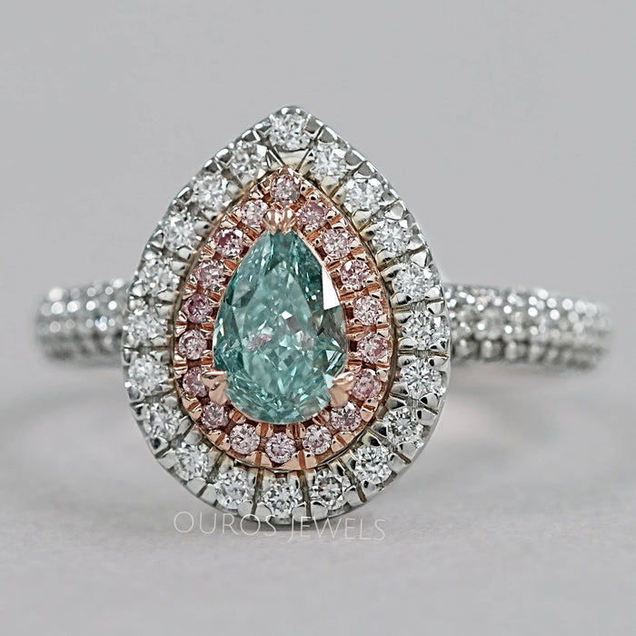 front view of green pear cut diamond double halo engagement ring on grey fabric