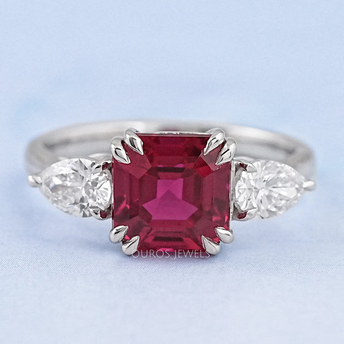 front view of asscher cut ruby and pear diamond double prong 3 stone wedding ring