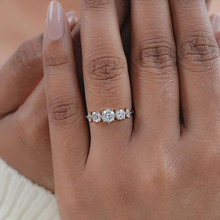 round and marquise cut lab diamond five stone engagement ring in finger
