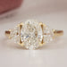 front view of oval cut diamond three stone engagement ring with yellow gold band