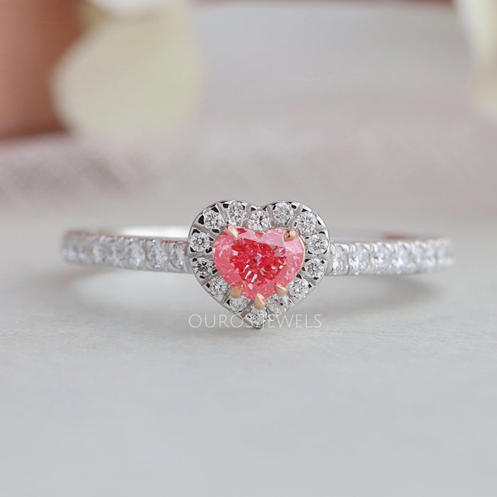 top view of pink heart cut diamond halo engagement ring on grey fabric