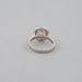 back view of pink round-cut diamond solitaire halo engagement ring on grey fabric