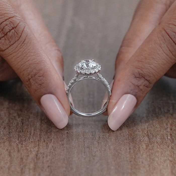 close view of round cut lab diamond halo engagement ring on brown background