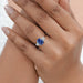 sapphire cushion gemstone with trapezoid diamond 3 stone wedding ring in finger