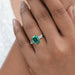 emerald gemstone and bullet-cut diamond three-stone engagement ring on model's finger
