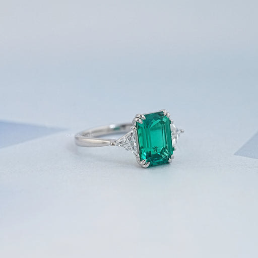 right view of emerald gemstone and triangle cut lab diamond 3 stone engagement ring