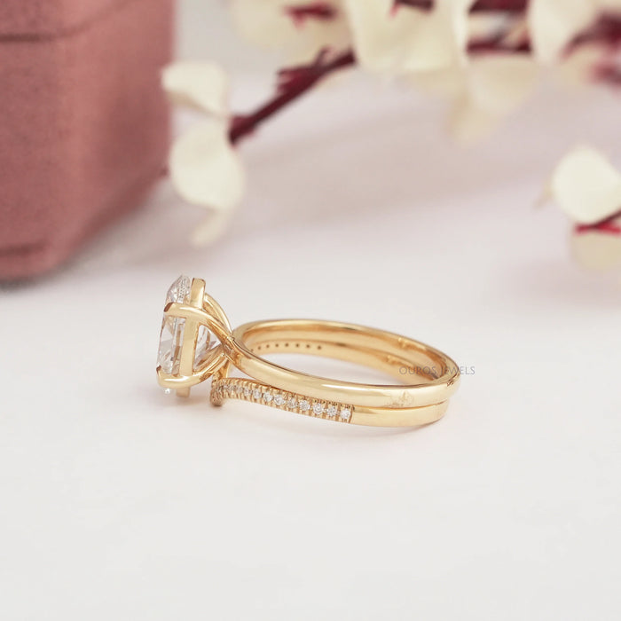 side view of oval-cut lab diamond curved bridal ring set with yellow gold band
