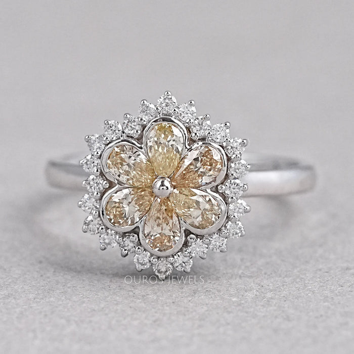 front view of yellow pear diamond floral halo engagement ring on grey fabric