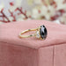 side view of black oval cut diamond three stone engagement ring on jewelry box