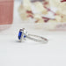 side view of blue cushion cut lab diamond halo engagement ring on grey fabric