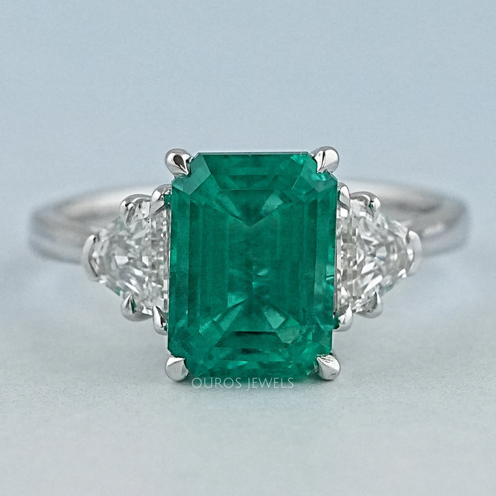 front view of green emerald gemstone with shield cut diamond 3 stone engagement ring