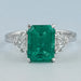 front view of green emerald gemstone with shield cut diamond 3 stone engagement ring
