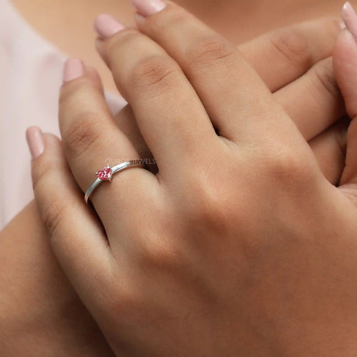 pink heart shape lab diamond solitaire engagement ring in model's hand