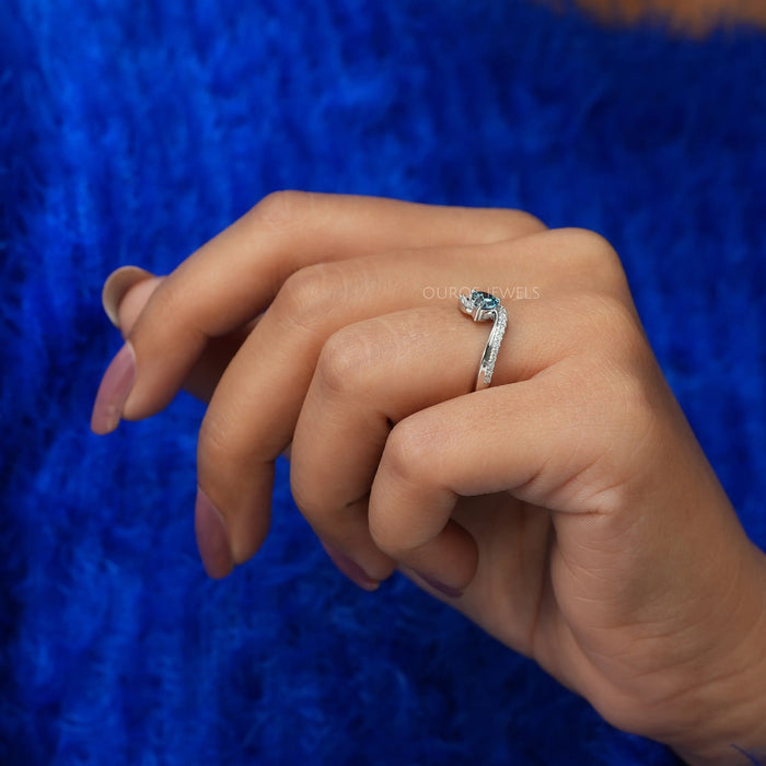 Lightly folded finger side view of heart shaped diamond engagement ring set in bypass.