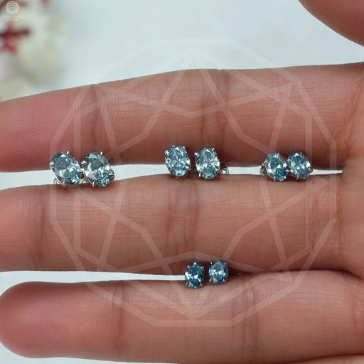 blue oval cut man made diamond studs earrings white gold shown on finger