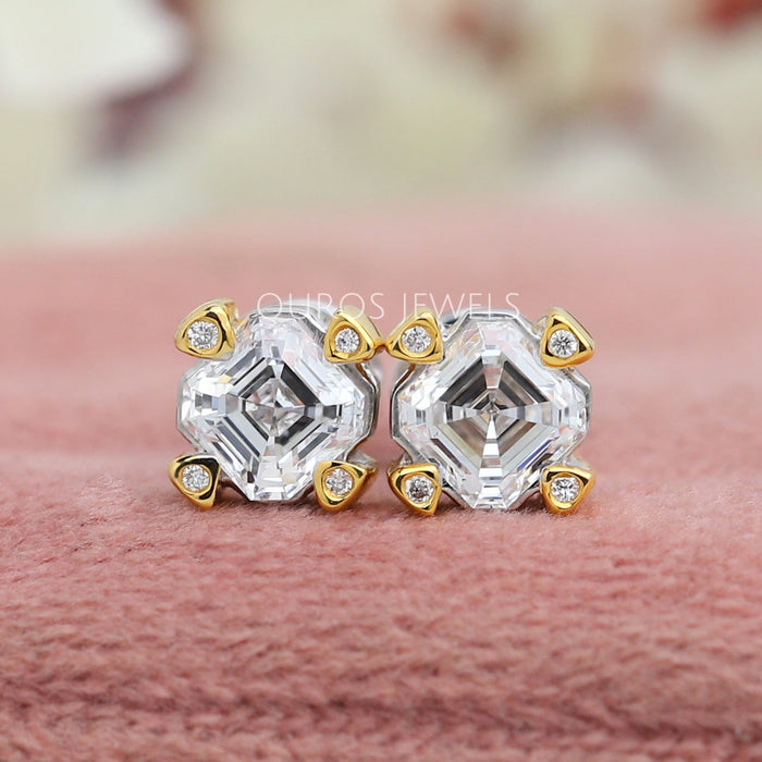 Asscher Cut Diamond Two Tone Stud Earrings, featuring intricate yellow gold and white gold settings with sparkling diamonds on a soft pink background.