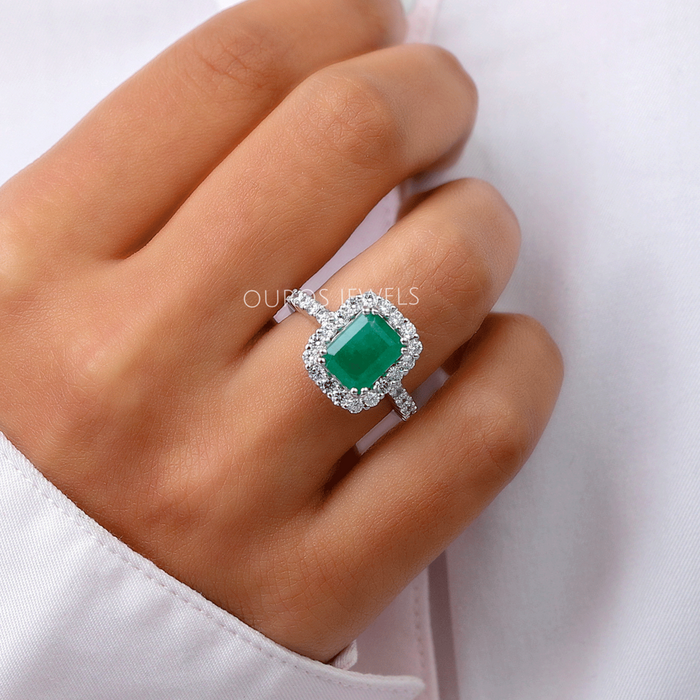 green emerald cut lab gemstone halo engagement ring in finger
